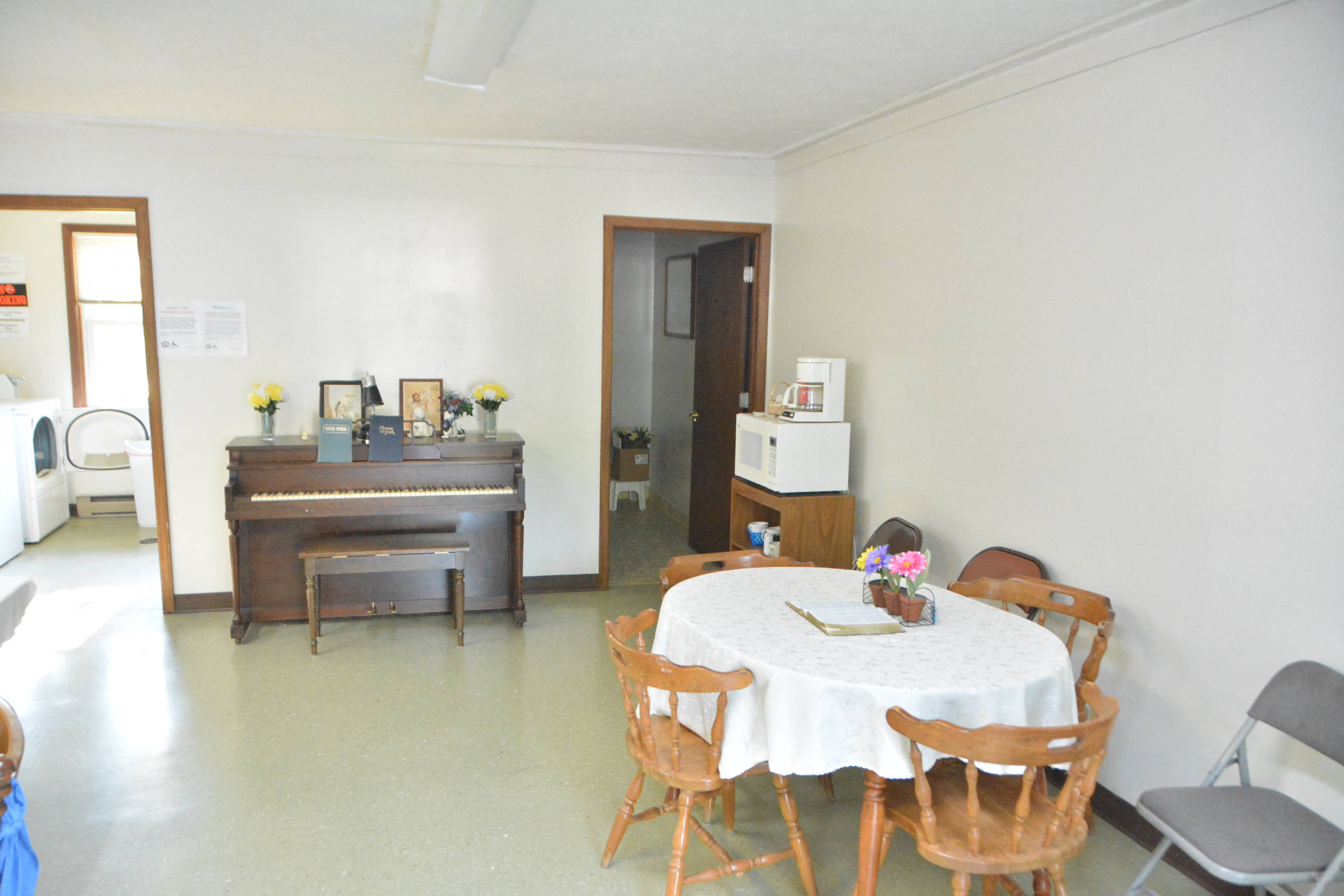 a dining room with a table and chairs and a piano
